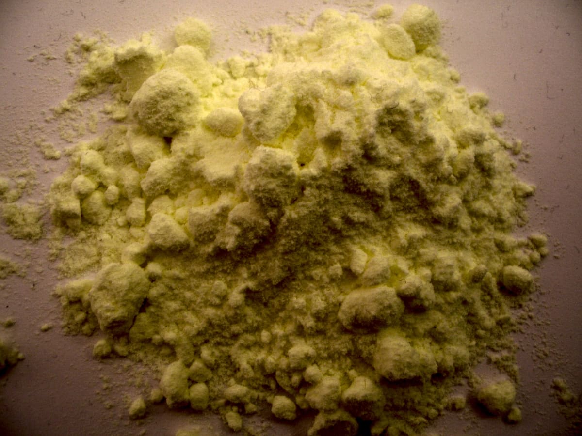 Un petit tas de poudre de soufre fine, jaune pâle, sur un fond clair